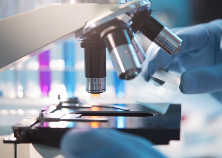 A scientist placing a slide under a microscope